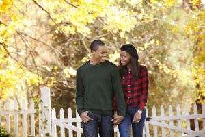 Young Couple Holding Hands and Walking Through Fall Leaves