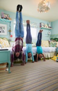 Black sisters performing handstands in bedroom