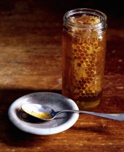 Jar of honey and spoon on wooden tabletop