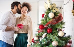 Young couple decorating a Christmas tree.
