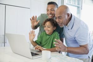 Happy boy with father and grandfather having video chat on laptop