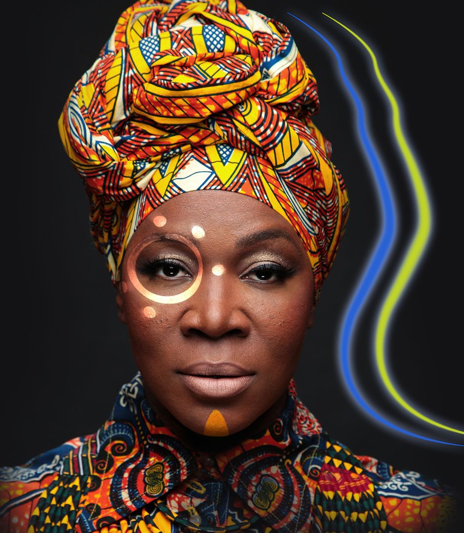 A colorfully dressed woman with an elaborate headpiece and bold makeup against a dark background, with text "INDIA ARIE THE WORTHY TOUR MAY 19 THEATRE AT GRAND PRAIRIE".