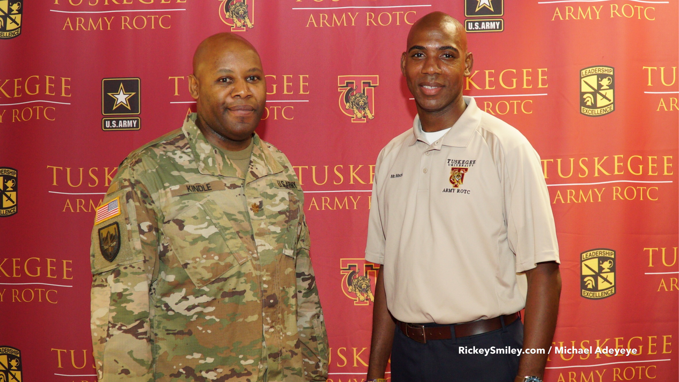 Two uniformed men standing in front of Tuskegee Army ROTC banners.